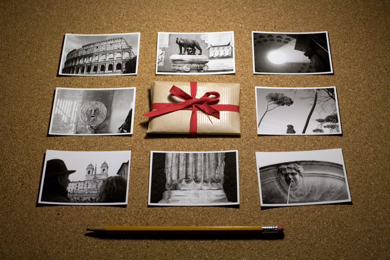 A photograph of the eight prints included in the Rome print packet and the pocket print packet itself, with a pencil present for size reference.